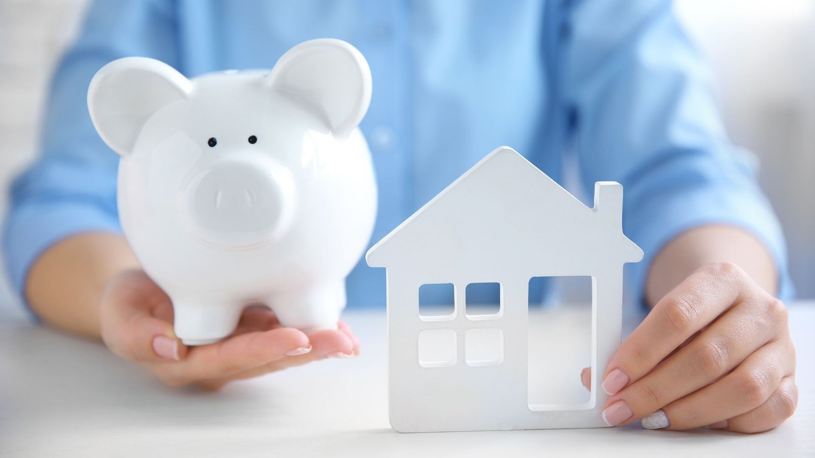 Man Showing Piggy Bank and House that represent Saving For a Down Payment For A House