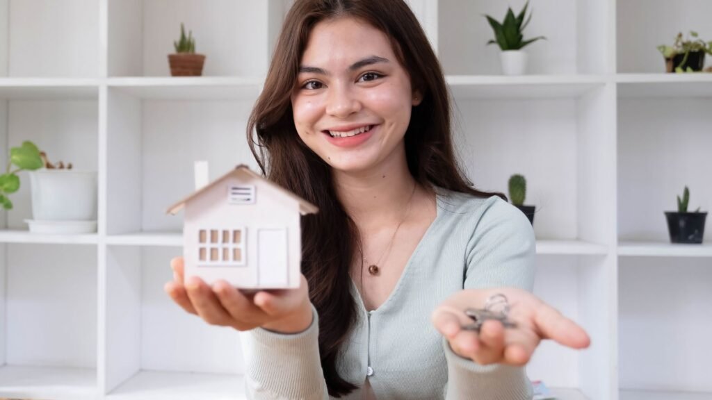 Young professional showing a miniature house and the key to her new home